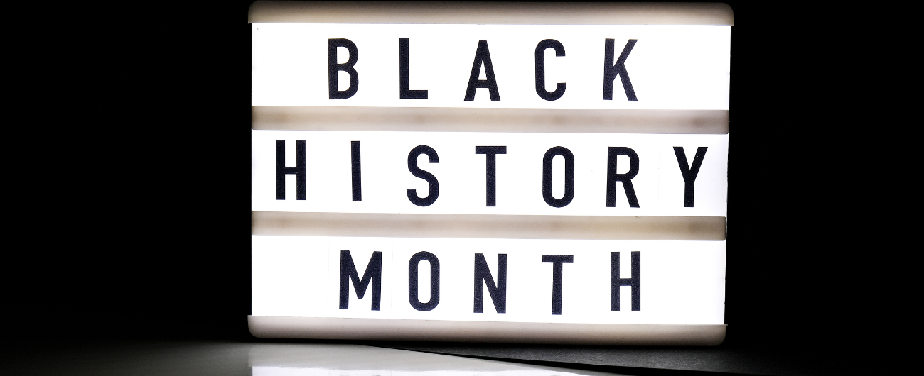 On a black background, words 'BLACK HISTORY MONTH' are written backlit on a white block.